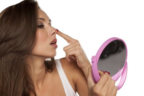 Girl after recovery looks at her nose in the mirror